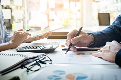 financial inspectors working with calculators and tablets in office